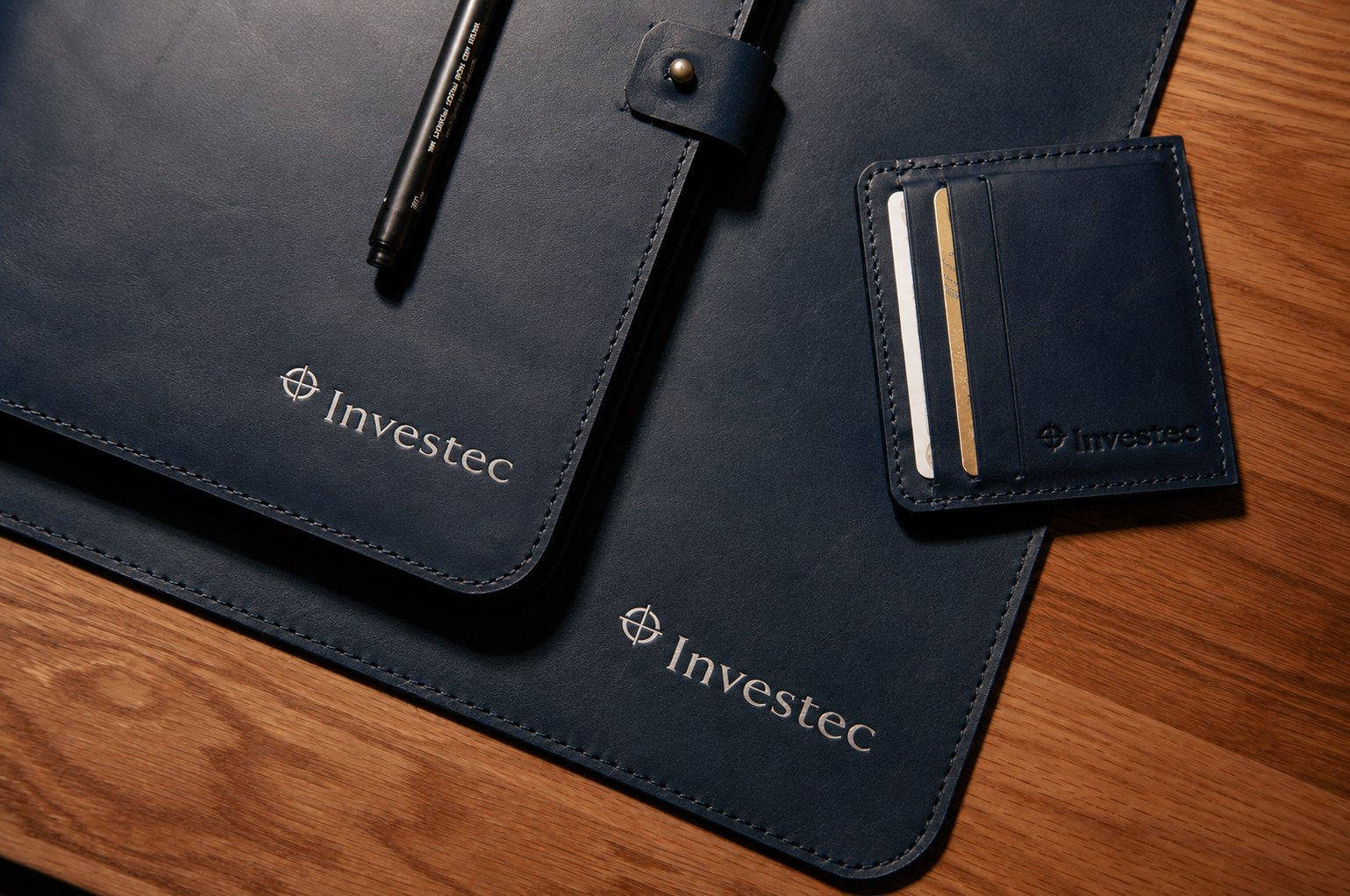 Investec branded navy leather desk mat and card holder with foiled logo