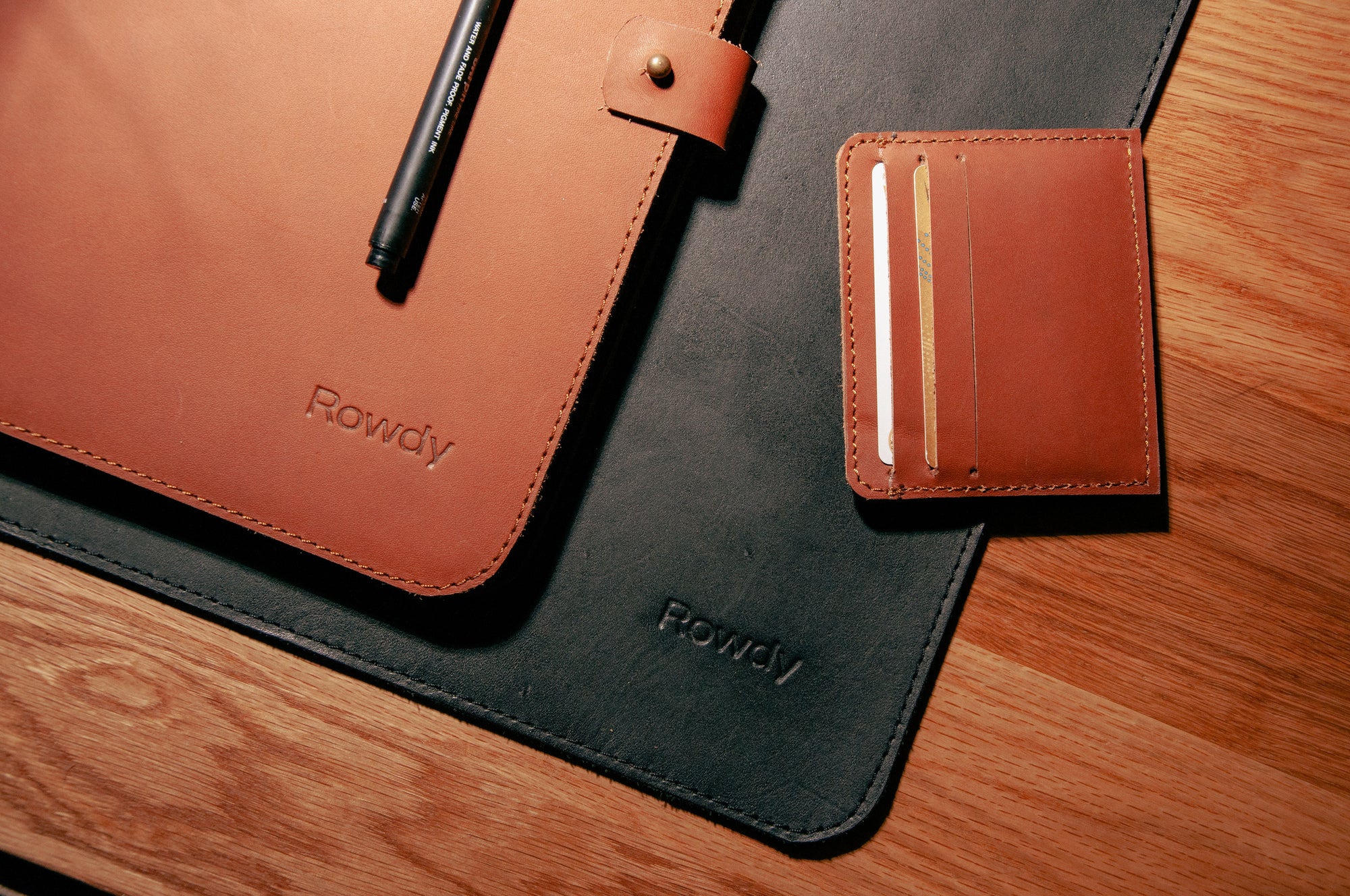 ROWDY corporate brown and black leather accessories flat lay