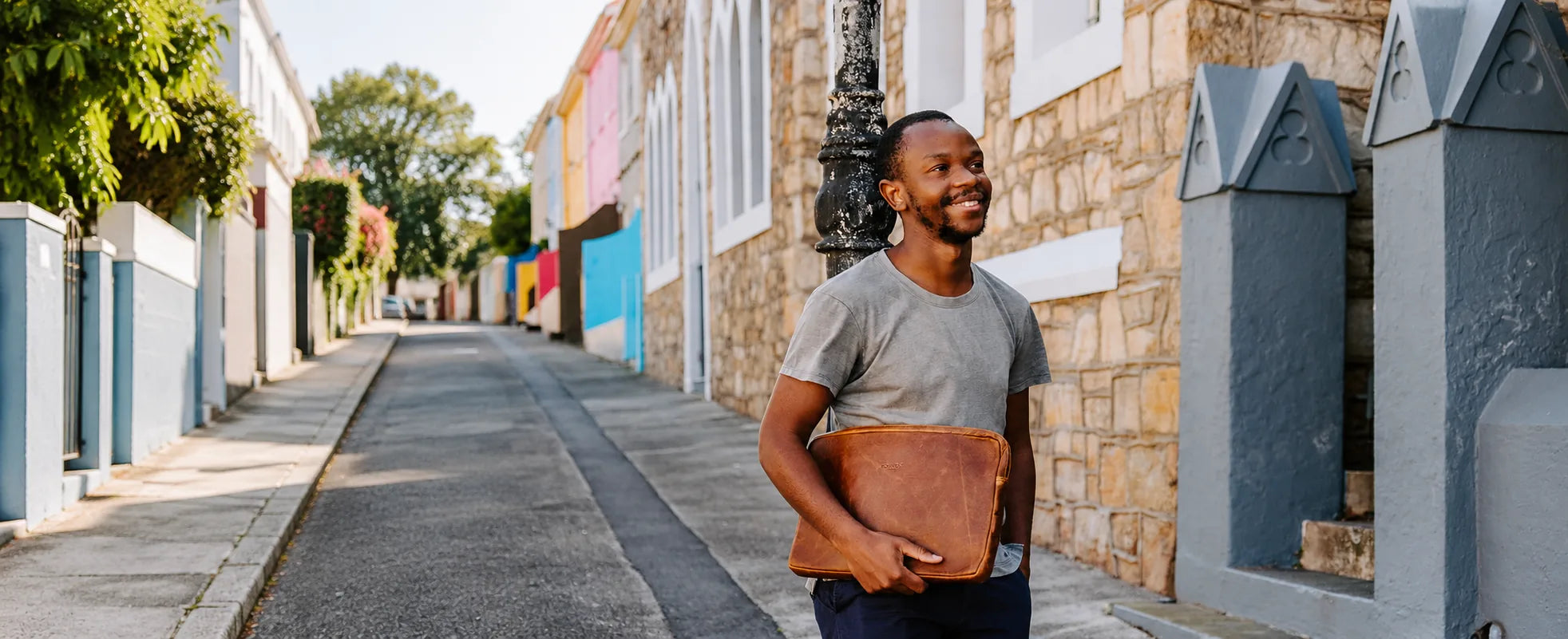Man walking down a Cape Town street carrying a Cedar leather Rowdy Laptop Sleeve